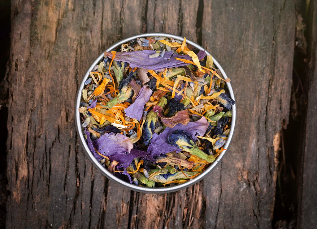 Curated collection of dried herbal blends in ceramic bowls arranged on natural linen